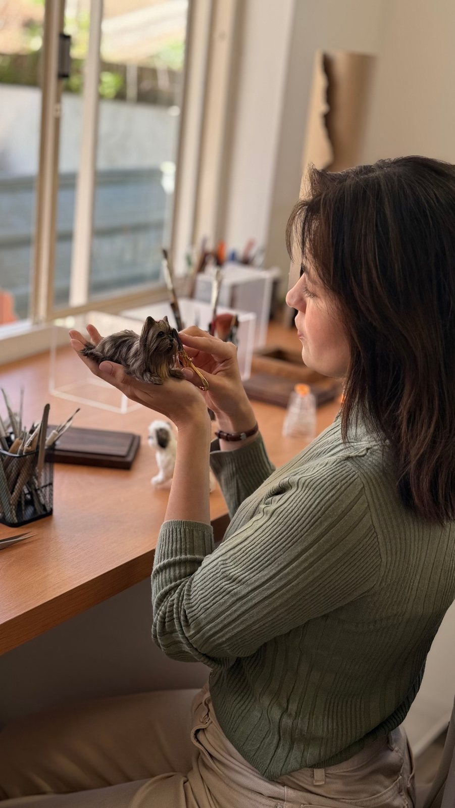 Jiceli Paola pintando uma miniatura no ateliê Denngo